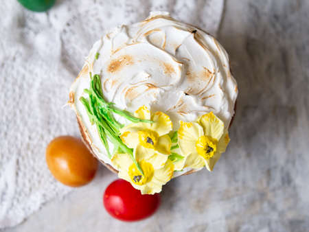 Easter cake kulich. Traditional Easter sweet bread decorated meringue, yellow daffodils on wooden gray background with lace fabric and colored egg. Copy space, top view. season's greetings cardの写真素材