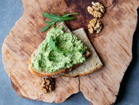 Arugula pesto with walnut. Sandwich with pesto on a wooden plate. Healthy breakfast. vegetarian food. Selective focus, copy space, close up, rustic. Keto dietの写真素材