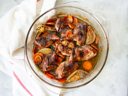 Delicious fried Quails with vegetables - garlic, carrots, onions , baked in a glass form with a light background. Dietary, gourmet lunch. Close up, selective focus.の写真素材