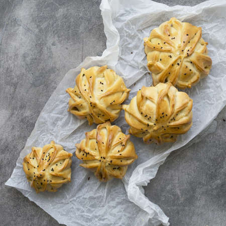 Interestingly shaped fresh meat mini pie on the gray table with white paper. Meat pies samosas with ground beef and spices. Menu, recipe concept. Selective focus. Closeup, top view, rustic styleの写真素材