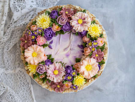 Napoleon cake with vanilla cream, decorated with buttercream flowers - roses, scabioses, chrysanthemums in pink, yellow, purple colors. Vintage style. Gray background, lace napkin. Copy spaceの写真素材