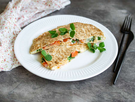 Vegetarian healthy breakfast of melted thin pita bread, cheese, tomato and herbs on a white plate and gray background. Diet. Selective focus, close up, copy spaceの写真素材