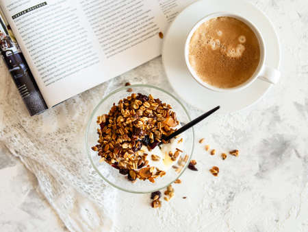 Healthy breakfast. Granola, muesli with pumpkin seeds, honey, yogurt in a glass bowl with a cup of coffee on white background. Breakfast of a modern girl. Close up, copy space.の写真素材