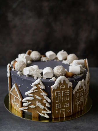 Christmas gray cake decoraited of gingerbread cookies in shape of homes and snowy christmas trees, marshmallows, snowflakes, sweets. Christmas, New Year greeting card. Gray background. Copy space.の写真素材