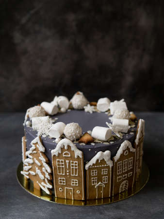Christmas gray cake decoraited of gingerbread cookies in shape of homes and snowy christmas trees, marshmallows, snowflakes, sweets. Christmas, New Year greeting card. Gray background. Copy space.の写真素材