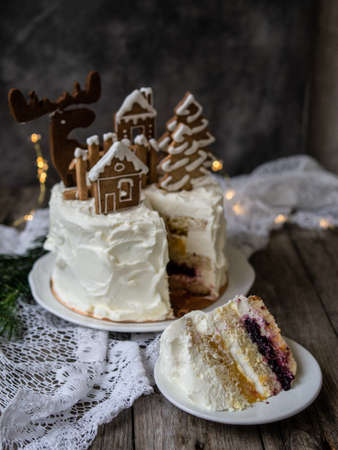 Christmas cake with gingerbread decorations - cookies in shape of homes and snowy trees, moose. Piece of cake. Christmas,New Year greeting card. Gray background with Christmas tree. Copy spaceの写真素材