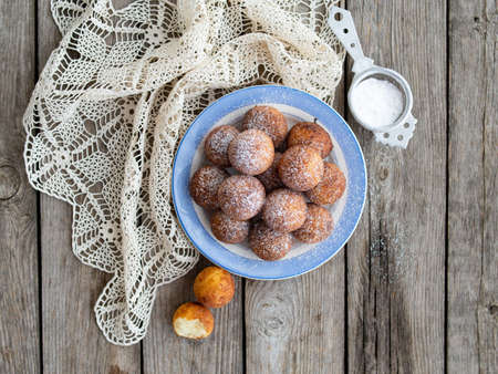Freshly baked cheese donuts with powdered sugar on the plate on wooden rustic table. The atmosphere of a cozy home breakfast. Close up, copy space.の写真素材