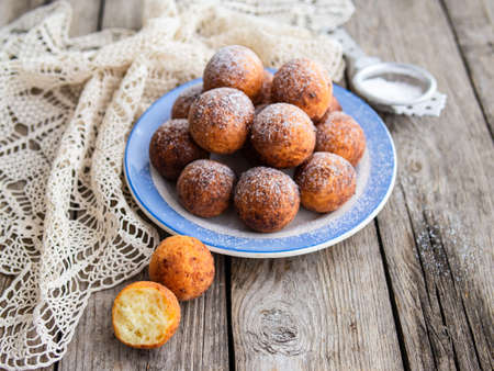 Freshly baked cheese donuts with powdered sugar on the plate on wooden rustic table. The atmosphere of a cozy home breakfast. Close up, copy space.の写真素材