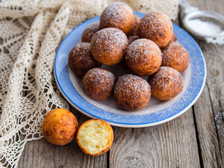 Freshly baked cheese donuts with powdered sugar on the plate on wooden rustic table. The atmosphere of a cozy home breakfast. Close up, copy space.の写真素材