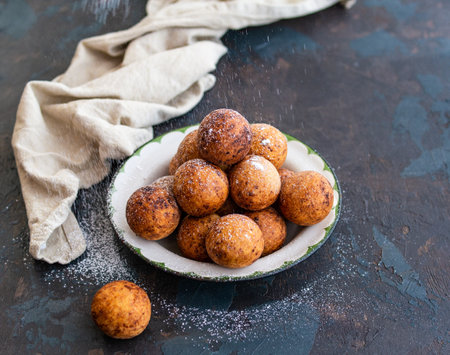 Beautiful breakfast. Cottage cheese donuts balls with sugar powder on a dark background. Close up. Copy spaceの写真素材