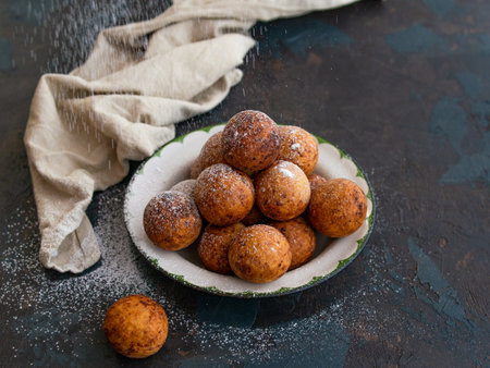 Beautiful breakfast. Cottage cheese donuts balls with sugar powder on a dark background. Close up. Copy spaceの写真素材