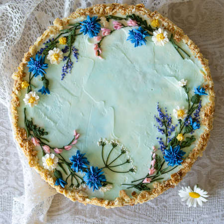 Napoleon cake with vanilla cream, decorated with buttercream flowers - summer wild flowers. Vintage style. Grey background, lace napkin, a bouquet of daisies. Copy space, close up.の写真素材