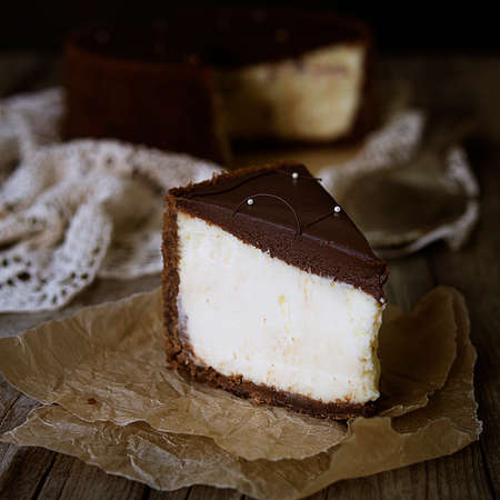 Slice of cheesecake with chocolate on plate, still life with a rustic brown background. Close up, copy space.の写真素材