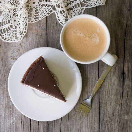 Plate with pieces of tasty cheesecake with chocolate and cup of coffee on wooden background. Rustic style. Top view. close upの写真素材