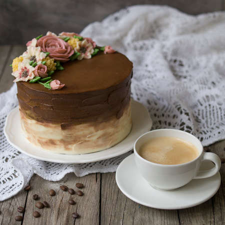 Coffe Tiramisu cake with cup of coffee on old wood table. rustic style. Cake with chocolate cream and decorated by cream flowers. Close up. Copy space.の写真素材