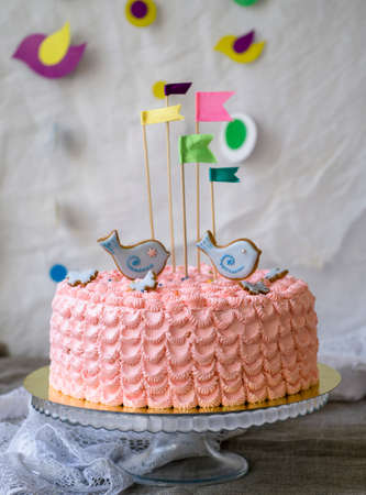 Pink birthday cake with birds topper and flags against a white background, space for text. Romantic love concept. Birthday Cake card Background. Buttercream. Copy space. close up.の写真素材