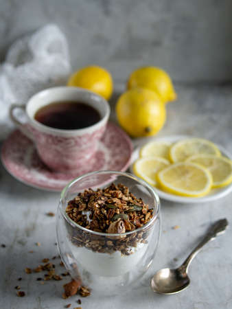 Healthy clean eating, dieting and nutrition, fitness, balanced food, breakfast concept. Homemade granola muesli with yogurt, cup of tea, lemons on a table.の写真素材