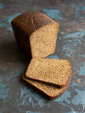 Sliced rye bread on cutting board on dark background. Copy space, close upの写真素材