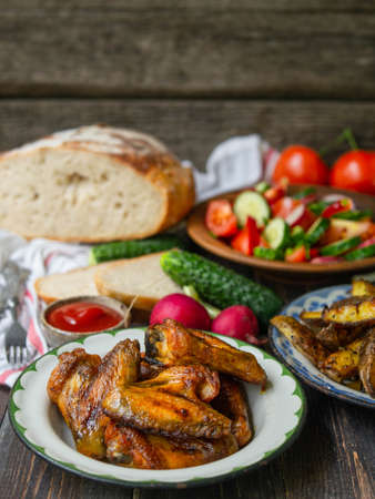 French fries, salad, vegetables on an old wooden background. Rural dinner, summer picnic. Close up.の写真素材