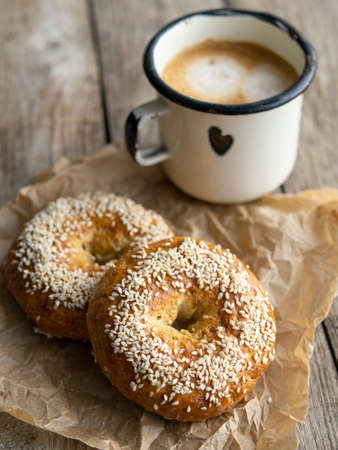 Fresh cheese donuts with sesame seeds on a wood background with metal white cup of coffee. Heathy food, diet, breakfast, lunch. Top view with copy space. retro, vitage.の写真素材