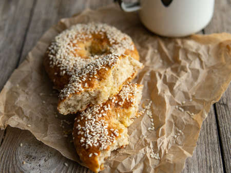 Fresh cheese donuts with sesame seeds on a wood background with metal white cup of coffee. Heathy food, diet, breakfast, lunch. Top view with copy space. retro, vitage.の写真素材