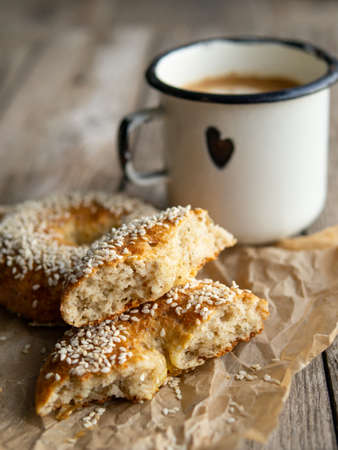 Fresh cheese donuts with sesame seeds on a wood background with metal white cup of coffee. Heathy food, diet, breakfast, lunch. Top view with copy space. retro, vitage.の写真素材
