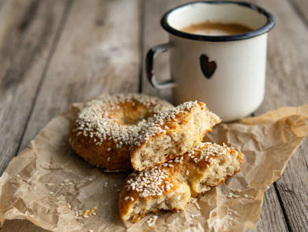 Fresh cheese donuts with sesame seeds on a wood background with metal white cup of coffee. Heathy food, diet, breakfast, lunch. Top view with copy space. retro, vitage.の写真素材