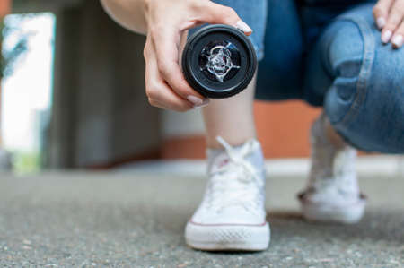 girl photographer dropped a photo lens on the asphalt, glass falls to the ground, close-up of a broken lens on the streetの写真素材