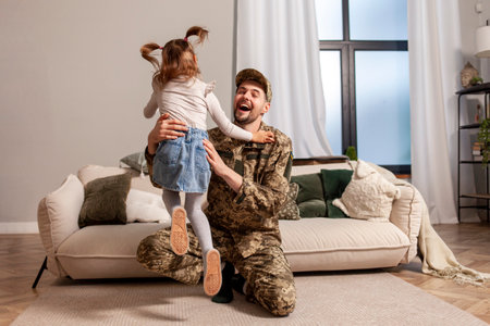 young soldier of the Ukrainian army in a camouflage uniform returned home to his child, a military dad meets and hugs his little daughter, happy girl runs and rejoices at the arrival of military dadの写真素材