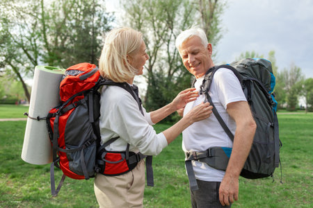 elderly athletic couple of seniors man and woman with hiking backpacks travel in the forest outdoors, gray-haired grandparents go hiking in natureの写真素材