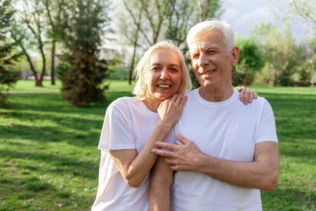 elderly couple of seniors man and woman hugging and smiling in the park outdoors, gray-haired...