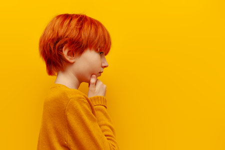 thoughtful red-haired teenage boy planning and thinking over yellow isolated background, serious child with orange hairstyle dreaming and imaginingの写真素材
