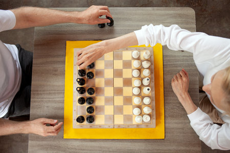 elderly senior couple playing chess outdoors in the park, old man and woman competing in a board...