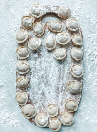 Beautiful dumplings are laid out on the board. In the background is a table covered in flour.の写真素材