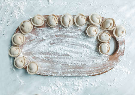 Beautiful dumplings are laid out on the board. In the background is a table covered in flour.の写真素材