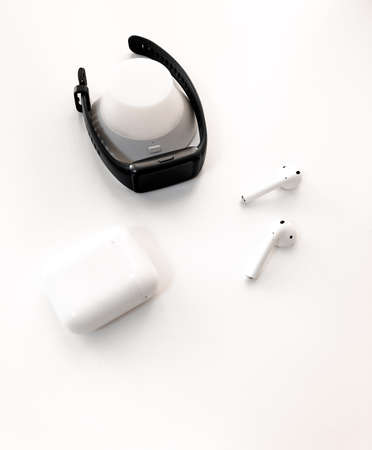 Fitness watches and wireless headphones lie on a beautiful white table.の写真素材
