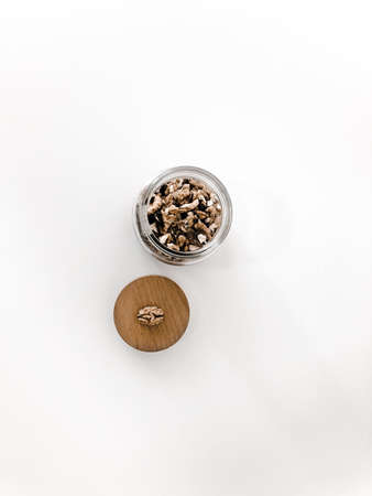 A jar of walnuts on a white table.の写真素材
