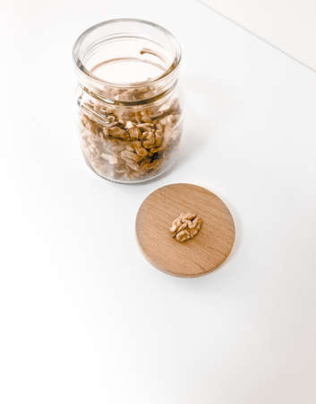 A jar of walnuts on a white table.の写真素材