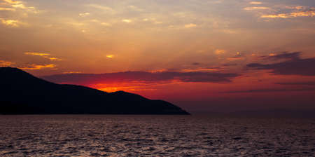 Dramatic sunset with red sky. Coastline silhouette in the backgroundの写真素材