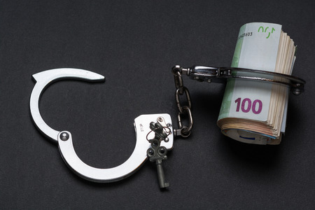 Money and handcuffs. Concept for corruption, fraud, money laundryの写真素材