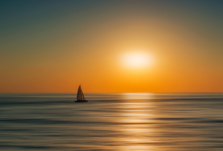 Silhouette of a boat at sunrise. Artistic blur effect added on the waterの写真素材