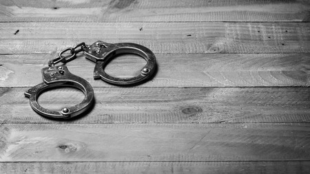 Handcuffs on a wooden tableの写真素材
