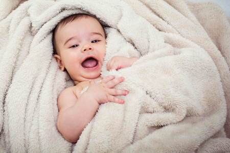 Cute baby boy in bed under a fluffy blanketの写真素材