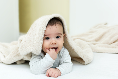 Cute baby boy in bed under a fluffy blanketの写真素材