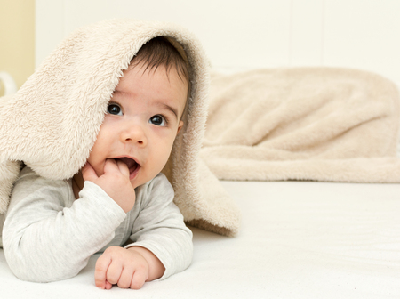 Cute baby boy in bed under a fluffy blanketの写真素材