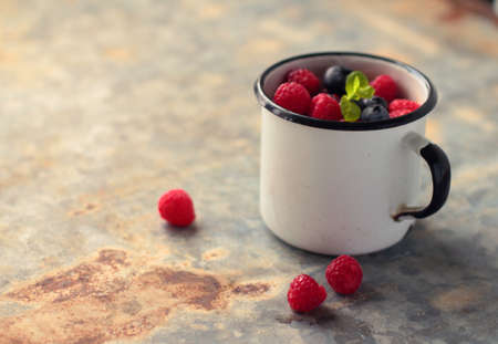 White enamel mug with fresh blueberry and raspberry fruitsの写真素材
