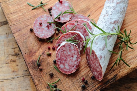 Salami sausage with herbs on a wooden boardの写真素材