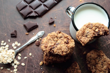 Oat cookies with dark chocolate and mug of milkの写真素材