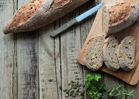 Bread slices on wooden board with fresh herbs