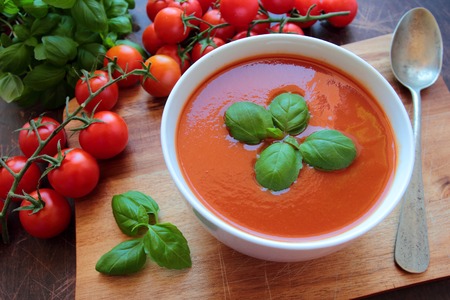 Bowl with tasty tomato soup on wooden boardの写真素材